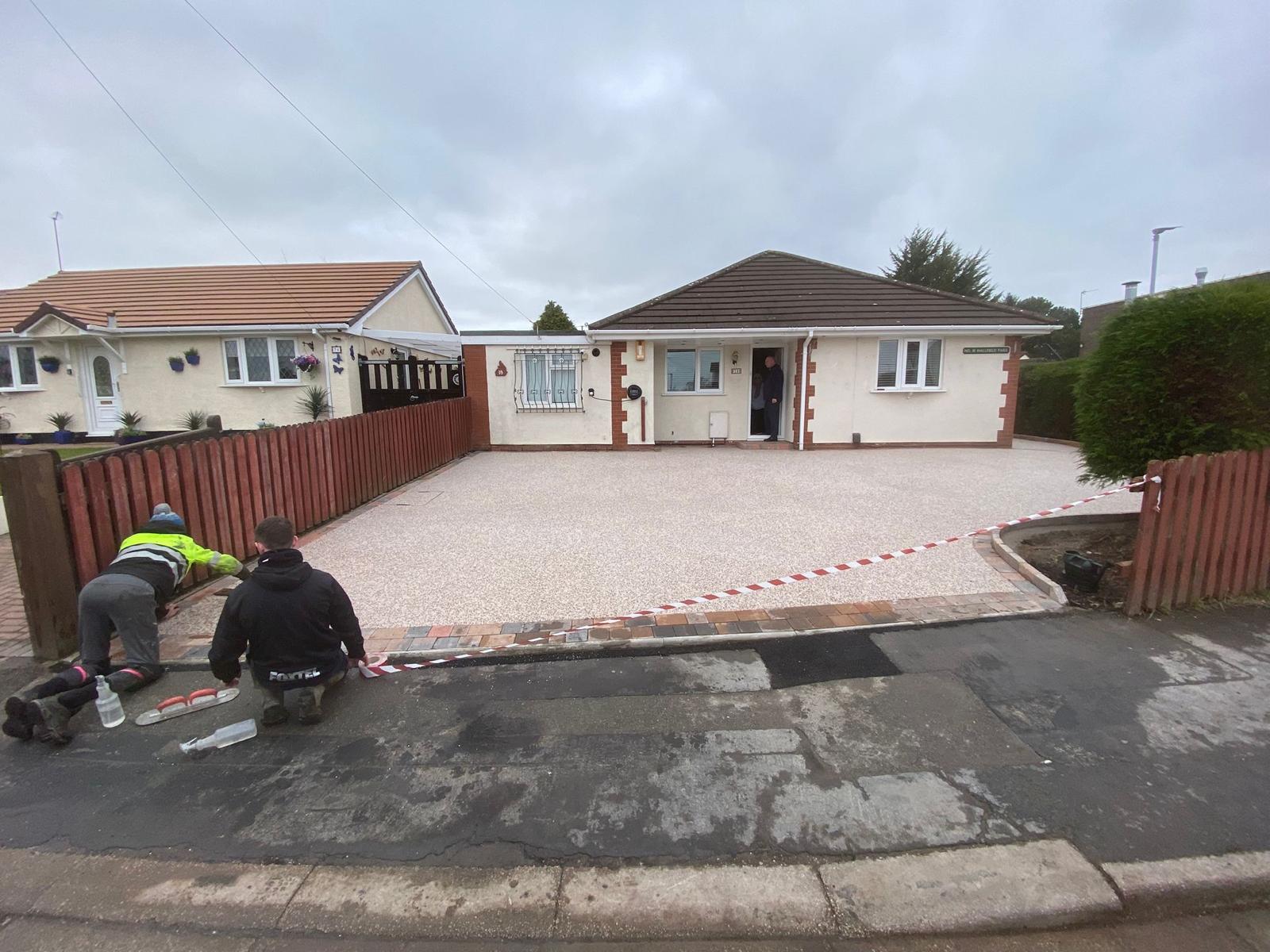 Resin bound surfacing being set out over the tarmac base