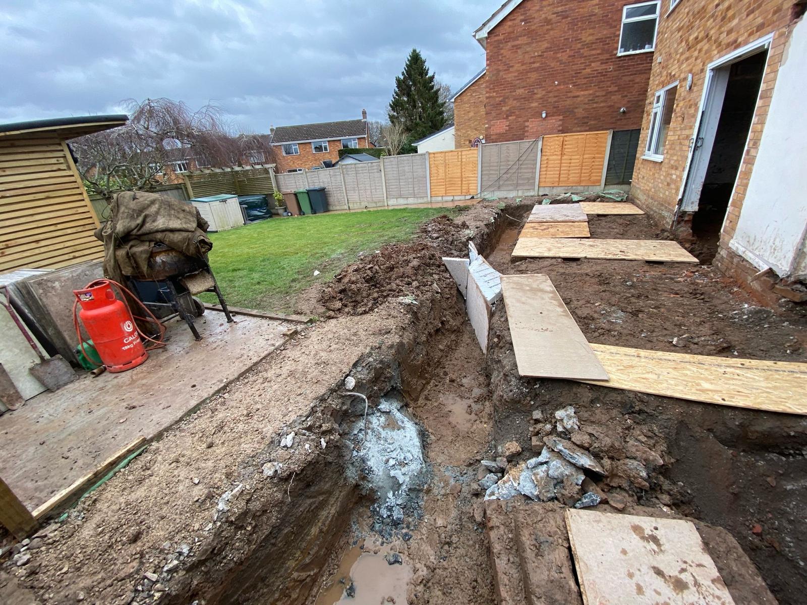 Drainage trench dug alongside the extension with boards over the excavation