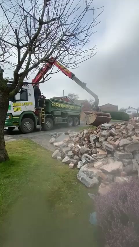 Grab lorry loading broken masonry from the front garden during muck-away