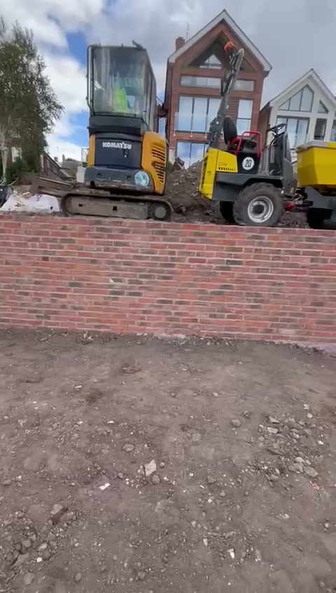 Excavator and dumper working on a cleared riverside garden