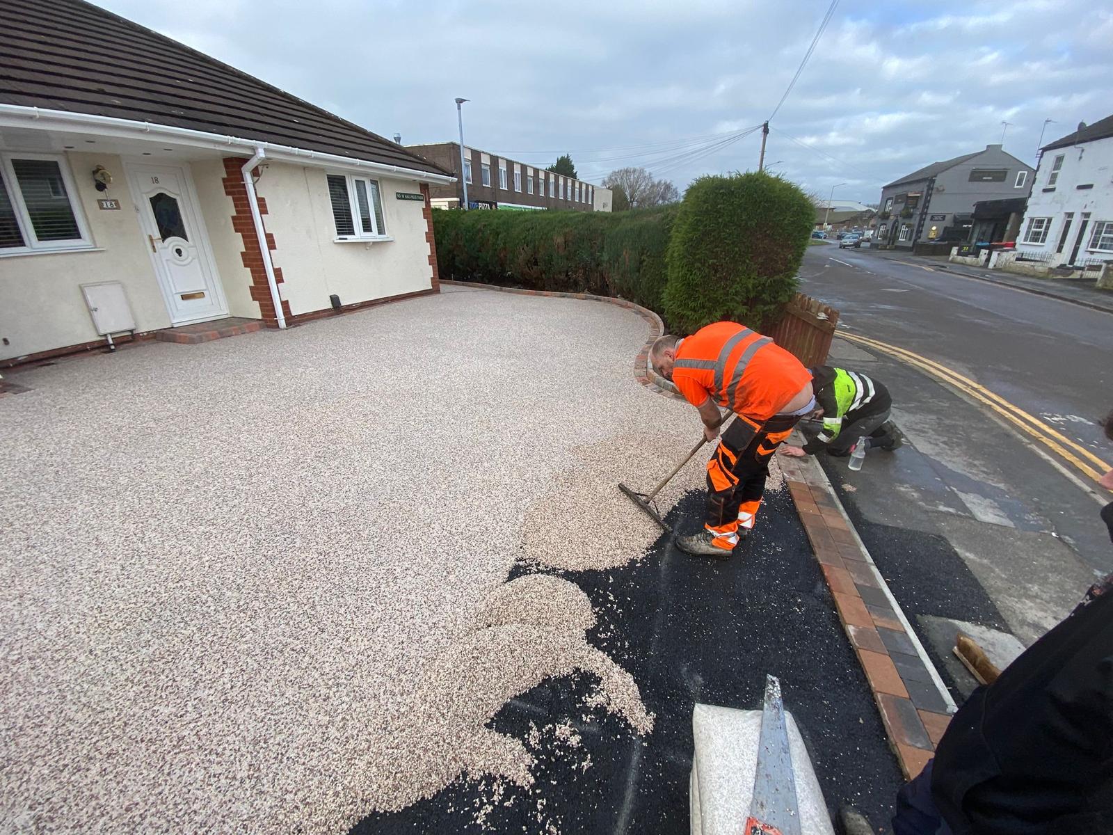 Installer trowelling buff resin bound gravel across the driveway