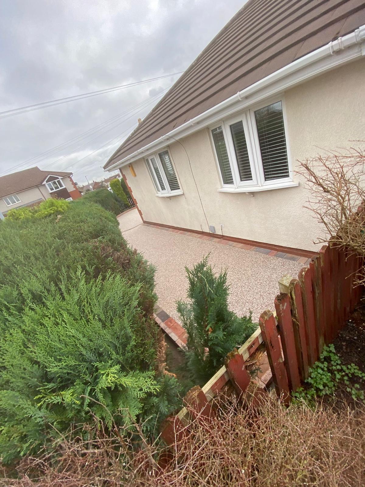 Buff resin bound driveway viewed from the road with brick sett kerb edging